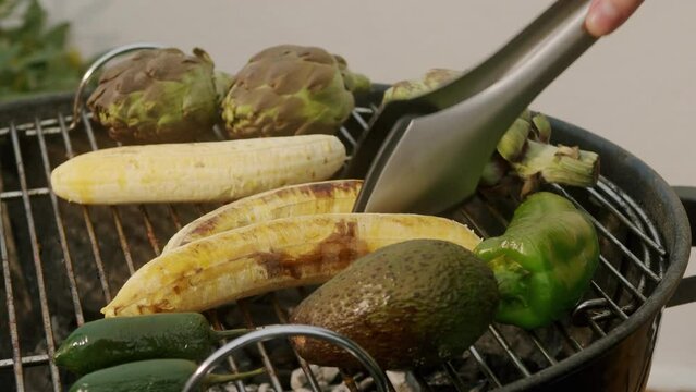 Grilled Banana on fire, latin american vegan grill with avocado and pepper, thai or Ecuadorian Street food. African traditional food on grill. 