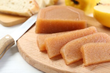 Tasty sweet quince paste, fresh fruits, bread and knife on white wooden table, closeup