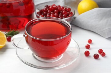 Tasty hot cranberry tea in glass cup and fresh berries on white table
