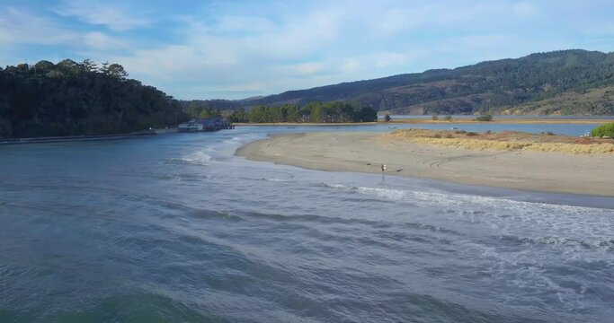 Aerial: Surfer entering water in seaside town of Stinson Beach and Bolinas, Marin near San Francisco, California, USA.