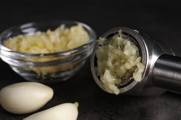 Garlic press, cloves and mince on grey table, closeup