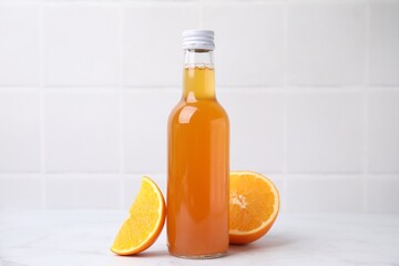Delicious kombucha in glass bottle and orange on white table