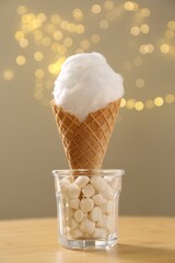 Sweet cotton candy in waffle cone on table against blurred lights