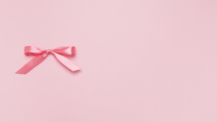 Pink bow on pink background. Top view, copy space