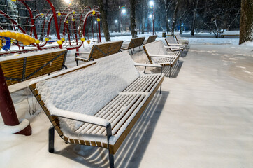 Benches in the snow on a winter evening in the park.