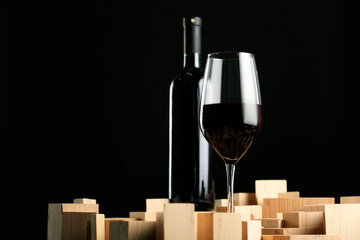 Stylish presentation of red wine in bottle and wineglass on black background