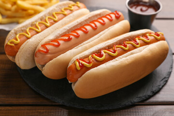 Delicious hot dogs with sauces on wooden table, closeup