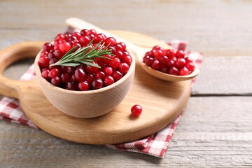 Fresh ripe cranberries and rosemary on wooden table