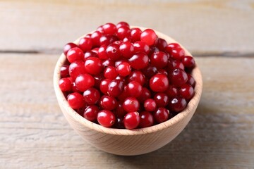 Fresh ripe cranberries in bowl on wooden table, closeup