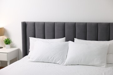 Soft white pillows and bedsheet on bed at home