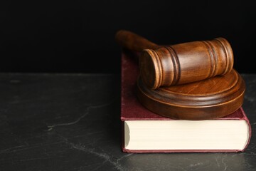 Wooden gavel, sound block and book on dark textured table, closeup. Space for text