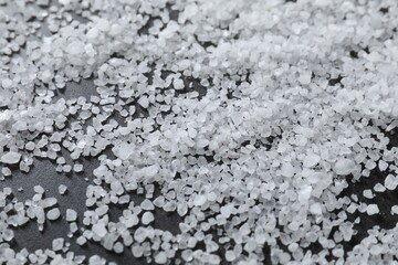 Scattered natural salt on black table, closeup