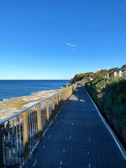 Obraz premium Boardwalk to the beach. Fence and bridge on the sea coast. Walkway near the blue turquoise ocean. Pier in the sea.