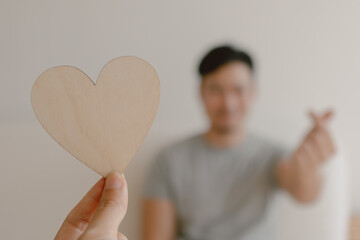 Photo of woman hand holding wooden blank empty space of heart design, showing and giving to asian man, showing love gesture, lovely couple marriage, valentines concept.