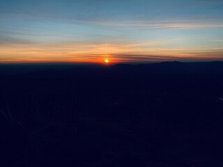 Coucher de soleil avec ciel orange et rouge, nuages colorés, et horizon illuminé, offrant un paysage panoramique de crépuscule et de lumière, avec des silhouettes et des couleurs vives en soirée.