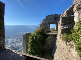 Fototapeta premium Paysage montagneux avec rochers anciens et murs de pierre, offrant une vue sur des falaises et des ruines historiques.