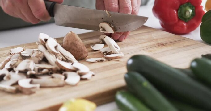 Close-up of hands chopping mushrooms on a cutting board in a home kitchen