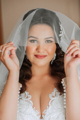 Beautiful young bride holding veil in white wedding dress, portrait of brunette bride in hotel...