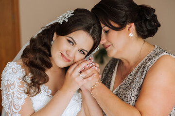 A beautiful and happy mother and her daughter, the bride, are standing next to each other. The best day for parents. Tender moments at the wedding.