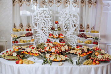 A banquet table full of fruits and berries, an assortment of sweets. Bananas, grapes, pineapples. Fruit compositions for the holiday.