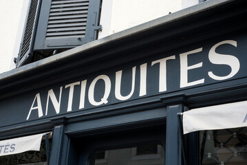 Closeup of antiques signage on store front in the street, traduction in english of antiquités in french - 740800054