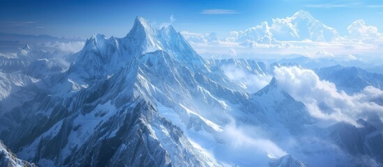 An aerial view of a snowcovered mountain with clouds hovering above, creating a serene natural landscape in the world of white snow and blue sky - obrazy, fototapety, plakaty