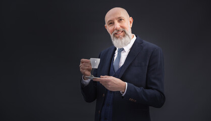Portrait corporate d'un homme d'affaires qui boit un café debout en souriant sur un fond gris