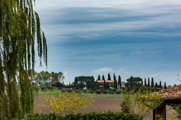 Autumn moody skies landscape in the mountain region of Tuscany, Italy with plowed fields, mist and beautiful cypress trees. Travel tourism destinations