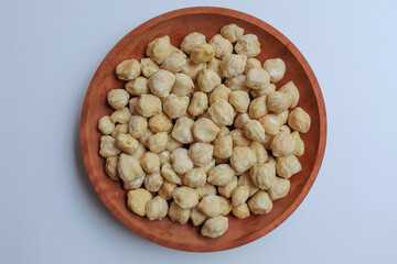 Dried Indonesian Candlenuts, or Kemiri, the seed of Aleurites moluccanus . On a wooden plate. Flat lay or top view