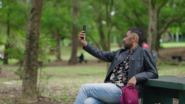 Selfie, hand gesture and face of  queer man at park taking pictures for social media with happy influencer. Portrait, profile picture and funny person outdoor.
