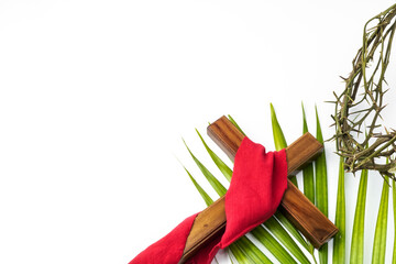 Jesus Wooden cross wrapped with red cloth with palm leaves and Crown of Thorns used by Catholic Christians on Good Friday Ceremony. Isolated on white background with empty blank copy text space. - obrazy, fototapety, plakaty