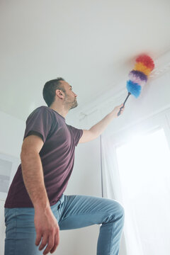 Man cleaning apartment with dusting broom.