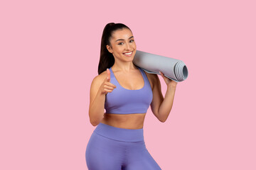 Happy woman with yoga mat giving thumbs up