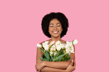 Content young African American woman with eyes closed, a serene smile, embracing a lush bouquet