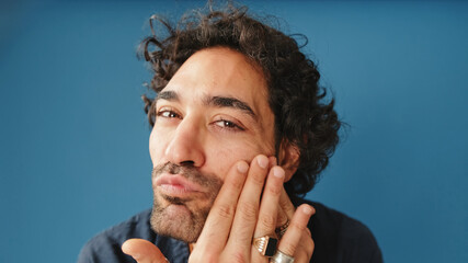 Close-up, man with curly hair, wearing blue shirt, looking at camera as if in mirror isolated on...