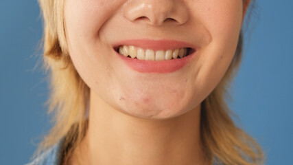 Detailed close-up shot of smile young woman, isolated on blue background