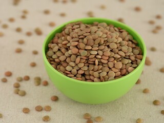 A green bowl full of lentils with lentils around it.