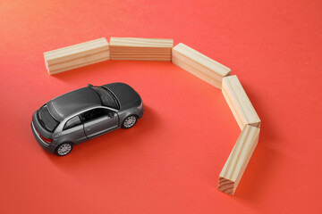 Development through barriers overcoming. Silver toy car movement blocked by wooden blocks on coral...