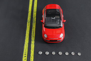 Pins as barrier blocking way for red toy car. Development through obstacles overcoming