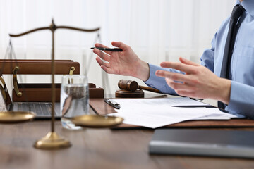 Lawyer with pen working at wooden table, closeup