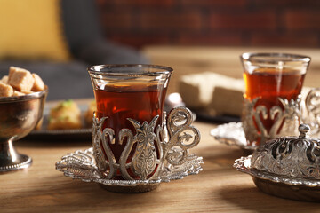 Glasses of traditional Turkish tea in vintage holders on wooden table