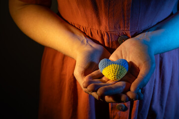 Support Ukraine concept, woman holding small heart colored in colors of ukrainian flag - 740821023