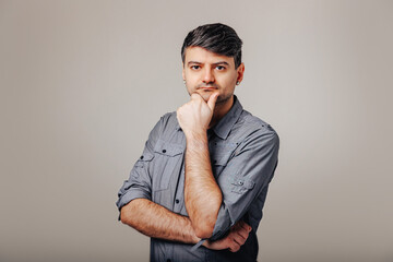 Man poses with his hand under his chin looking at the camera