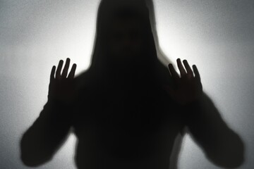 Silhouette of ghost behind glass against grey background