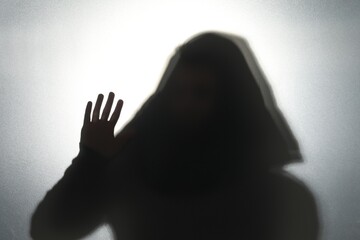 Silhouette of ghost behind glass against grey background