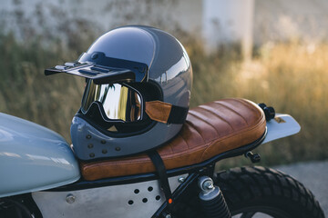 Motorcycle helmet with protective glasses on the seat of the cafe racer.