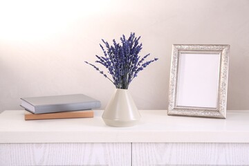 Bouquet of beautiful preserved lavender flowers, notebooks and blank photo frame on white wooden...