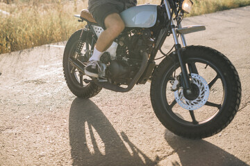 Biker on a cafe racer motorcycle on the road at sunset.