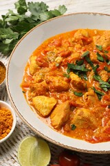 Delicious chicken curry and ingredients on table