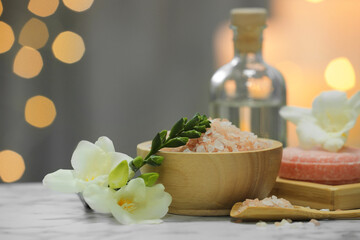 Beautiful composition with different spa products and flowers on white marble table against blurred...